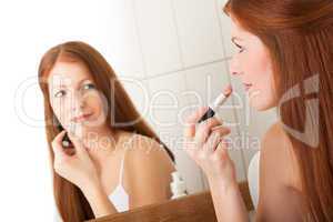 Body care series - Beautiful red hair woman applying lipstick