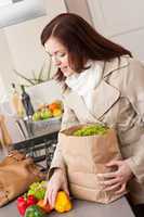 Young woman unpacking shopping bag in kitchen