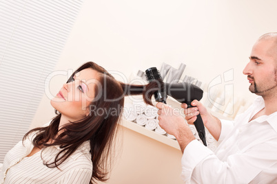 Professional hairdresser with hair dryer at salon with customer