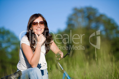 Woman with old-fashioned bike in summer meadow