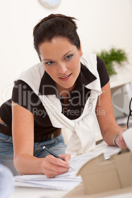 Young female architect writing with pen