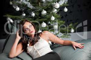 Provocative sexy woman posing in front of Christmas tree