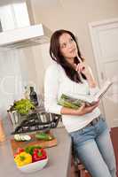 Beautiful woman holding cookbook in the kitchen