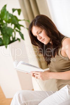 Young happy woman read book on sofa