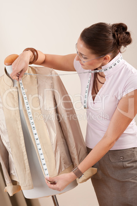 Female fashion designer taking measurement