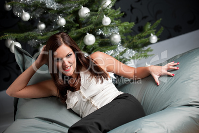 Provocative sexy woman posing in front of Christmas tree