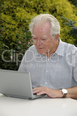 Alter Mann mit Netbook im Garten