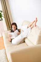 Young happy woman read book on sofa