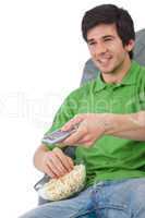 Young man holding remote control watch television