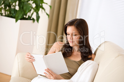 Young happy woman read book on sofa