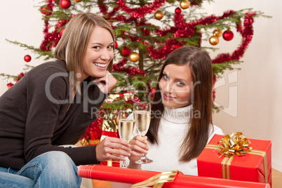 Two young woman with champagne and Christmas tree