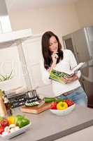 Young woman reading cookbook in the kitchen