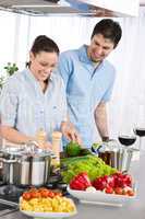 Smiling couple drink red wine cooking in kitchen