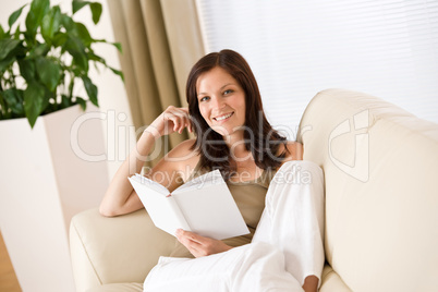 Young happy woman read book on sofa