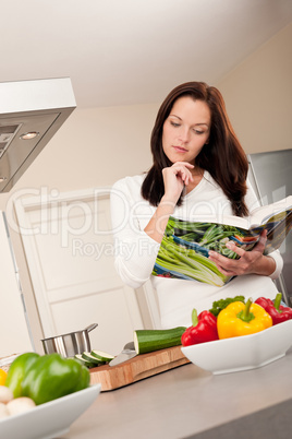 Young woman reading cookbook in the kitchen