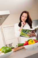 Young woman reading cookbook in the kitchen