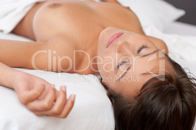 Naked woman sleeping in white bed, shallow DOF