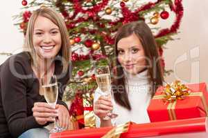 Two young woman with champagne and Christmas tree