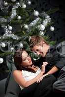 Extravagant man and woman in front of Christmas tree