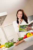 Young woman reading cookbook in the kitchen