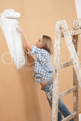 Home improvement: Woman painting wall with paint roller