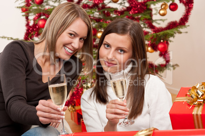 Two young woman with champagne and Christmas tree