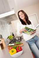 Young woman reading cookbook in the kitchen