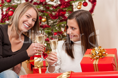 Two young woman with champagne and Christmas tree