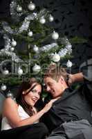 Extravagant man and woman in front of Christmas tree