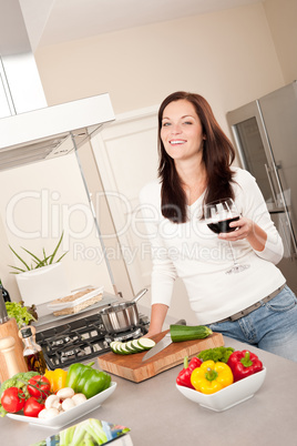 Young woman with glass of red wine in the kitchen