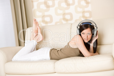 Happy woman with headphones on sofa in lounge