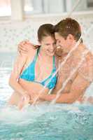 Young loving couple have fun under water stream in pool