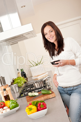 Young woman with glass of red wine in the kitchen