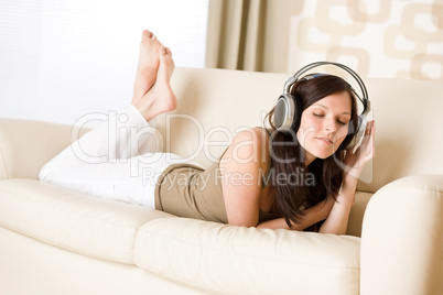 Happy woman with headphones on sofa in lounge