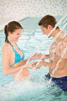 Swimming pool - young couple play under water stream