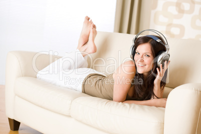 Happy woman with headphones on sofa in lounge