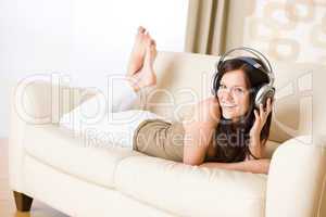 Happy woman with headphones on sofa in lounge