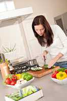 Happy woman cutting zucchini in the kitchen