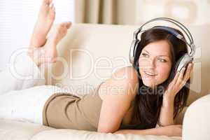 Happy woman with headphones on sofa in lounge