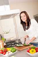 Smiling happy woman cutting zucchini in the kitchen