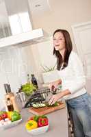Smiling happy woman cutting zucchini in the kitchen