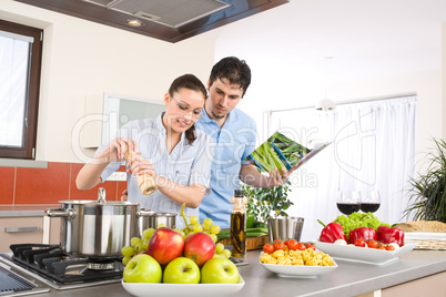 Young happy couple cook in kitchen with cookbook