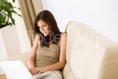 Smiling woman sitting with laptop on sofa