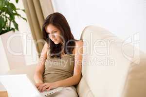 Smiling woman sitting with laptop on sofa
