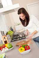 Young woman cutting bread in modern kitchen