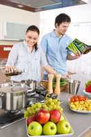 Young happy couple cook in kitchen with cookbook