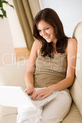 Smiling woman with laptop on sofa in lounge