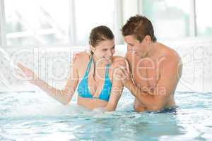 Young sportive couple have fun under water stream in pool