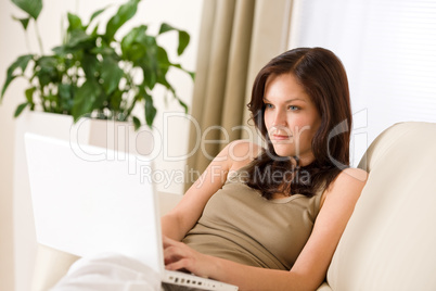 Smiling woman sitting with laptop on sofa