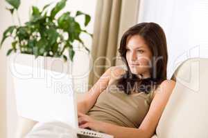 Smiling woman sitting with laptop on sofa